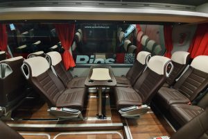 Vista interior Mercedes Tourismo con mesas y asientos enfrentados. Sólo previa petición expresa y según disponibilidad.
